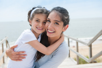 Obraz premium beautiful mom and her daugther at seaside smiling at camera