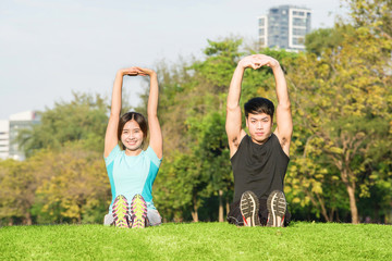 Obraz premium Young couple stretching before exercise together in park