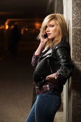 Young fashion blond woman in leather jacket calling on mobile ph
