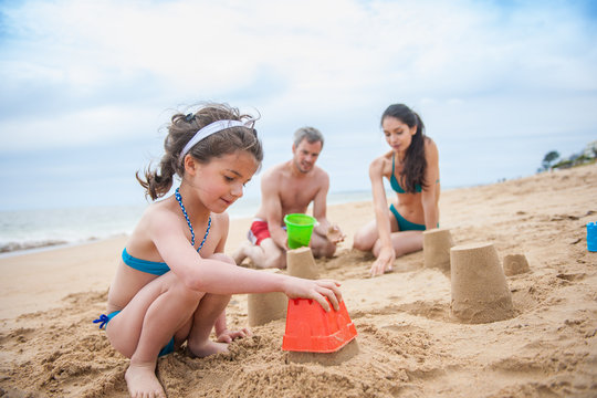 A young couple is playing at the beach with their daughter