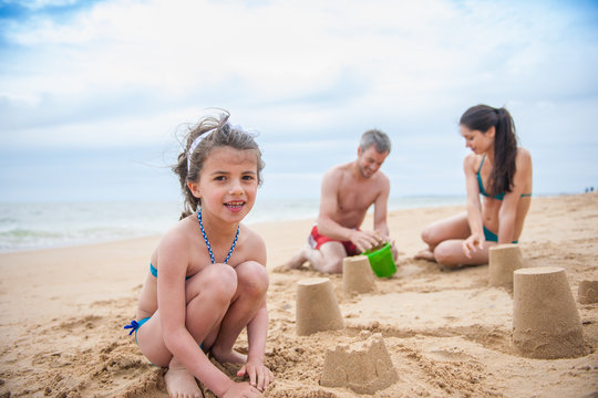 A young couple is playing at the beach with their daughter
