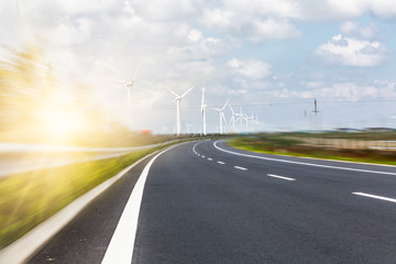 Wind turbines on landscape along empty road against sky