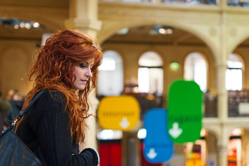 Portrait of young redhead woman inside public library.