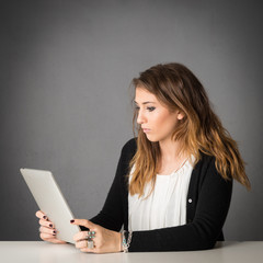 Woman using tablet against grey grunge background.