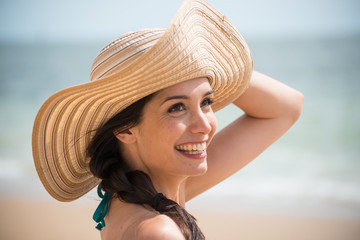 Portrait of a beautiful girl with a big hat at the beach