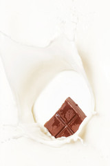 Dark chocolate splashed into fresh milk with white background.