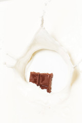 Dark chocolate splashed into fresh milk with white background.
