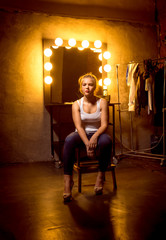 blonde woman posing on chair at dressing room in theater