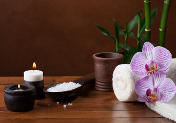 Spa setting with sea salt, candles, towels, stones and orchids.
