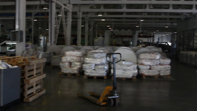 People work in large warehouse with goods at factory