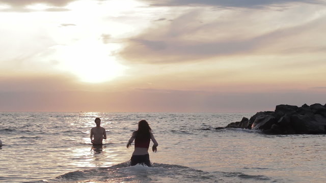 girl in love runs to her boyfriend into the sea - hugs and kisses - sunset