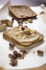 Fototapeta na wymiar pumpernickel bread with peanut butter and peanuts on paper