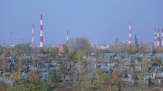 Cemetery on the background of an oil refinery, symbolic picture
