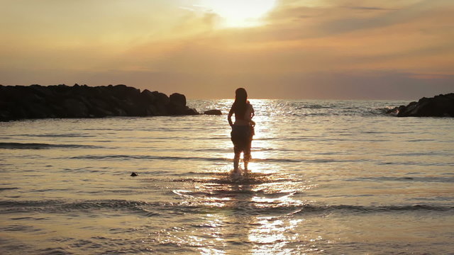 dressed woman in love runs to her man into the sea - hugs and kisses - sunset