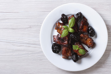 Pork ribs stewed with prunes on a plate. horizontal top view