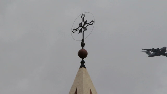 view of the cross of a church with a plane flies over