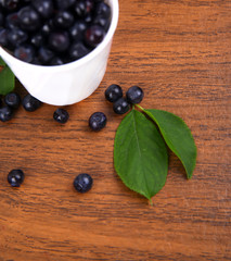 blueberries with leaf in bowl, cup on wooden background