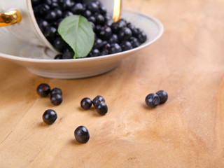 blueberries with leaf in bowl, cup on wooden background