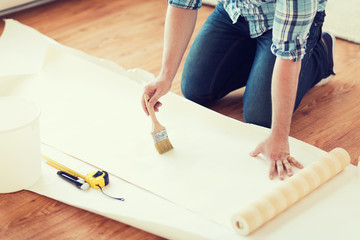 closeup of male hands smearing wallpaper with glue