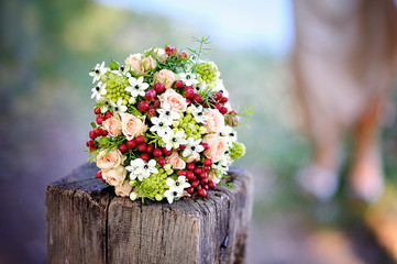 beautiful wedding bouquet with red flowers lying on a tree stump