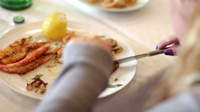 woman eats fish in seafood restaurant