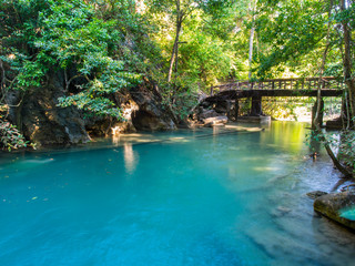 River flowing through from Erawan waterfall in deep forest of national park, Thailand with a bridge background.