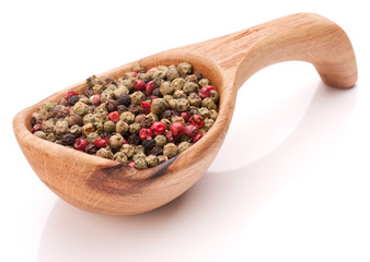 Black, green and pink pepper peppercorn mix in wooden spoon isol