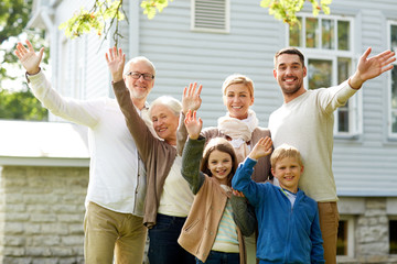 happy family waving hands in front of house