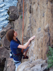 Girl climbing up a cliff.