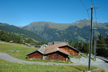 Fototapeta na wymiar Peaks, wooden buildings and railway tracks nearby Grindelwald.
