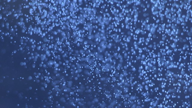 Dark blue underwater abyss shot with bubbles moving left to righ