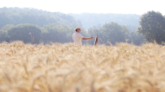 painter in the middle of a cornfield field paints a beautiful landscape, easel