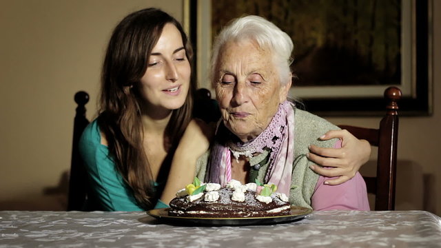 Old and young woman blow out her birthday candles.