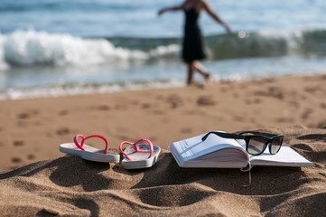 Reading book at beach with girl walking in the background 