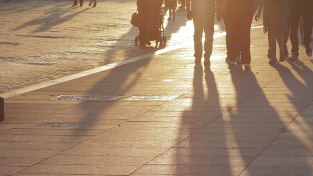 People walking at sunset, long shadows of people in silhouette anonymous