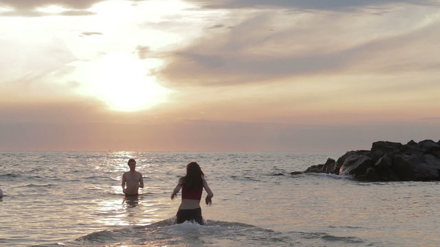 dressed woman in love runs to her man into the sea - hugs and kisses - sunset