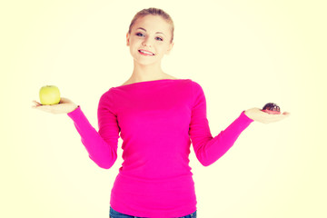 Young woman holding an apple and cookie.