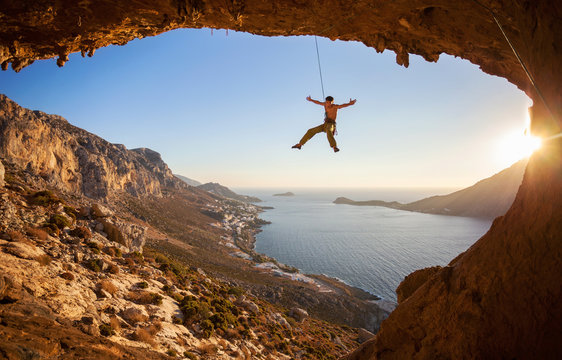 Rock Climber Hanging On Rope While Lead Climbing At Sunset