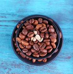 Coffee beans in black ceramic cup on blue wooden background