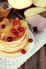 Stack of delicious pancakes with slices of apple and berries