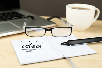 Cup of coffee with note Idea in notebook and glasses