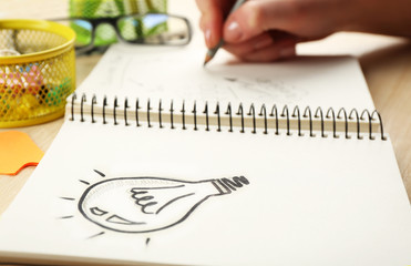 Female hand writing at notebook at wooden desk background