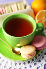 Colorful macaroons with cup of tea on wooden background