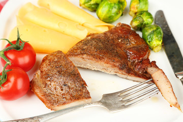 Roasted meat and vegetables on plate, on wooden table