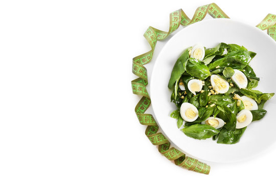 Salad with quail egg and basil in plate isolated on white