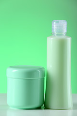Cosmetic bottles on light green background