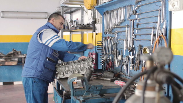 Auto mechanic repairing a car engine with socket wrench - dolly