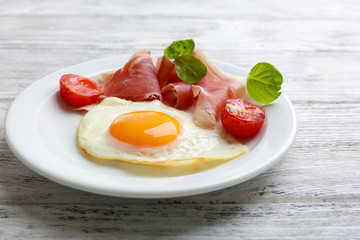 Bacon and eggs on color wooden table background.