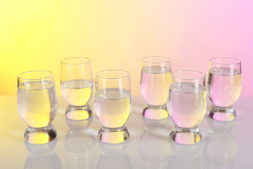 Glasses of water on table and colorful background
