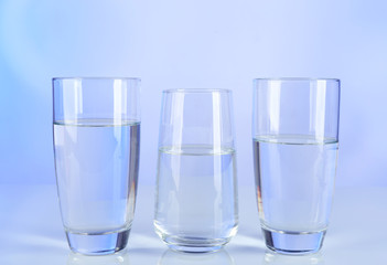 Glasses of water on table and colorful background